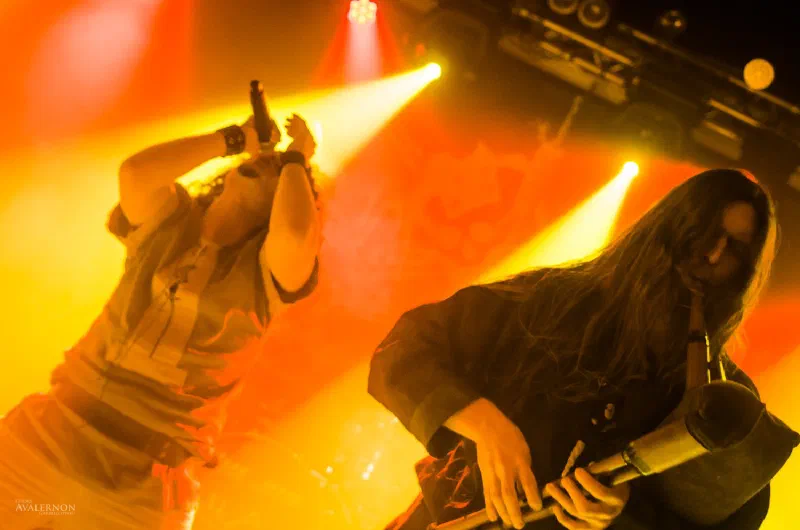 Singer and guitarist under orange stage lights