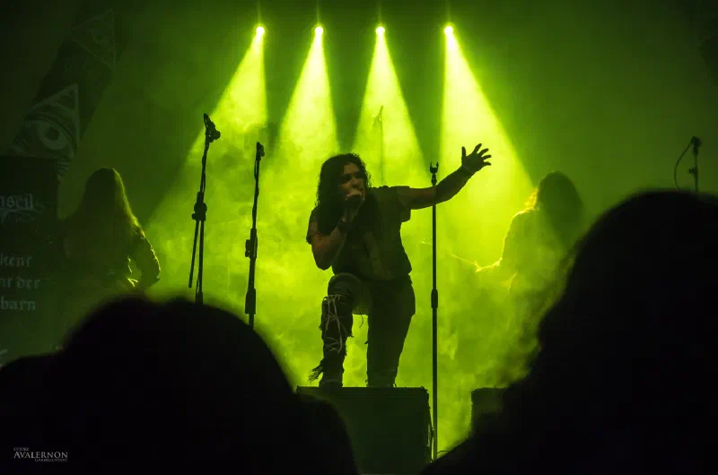 The singer backlit by green lights and smoke