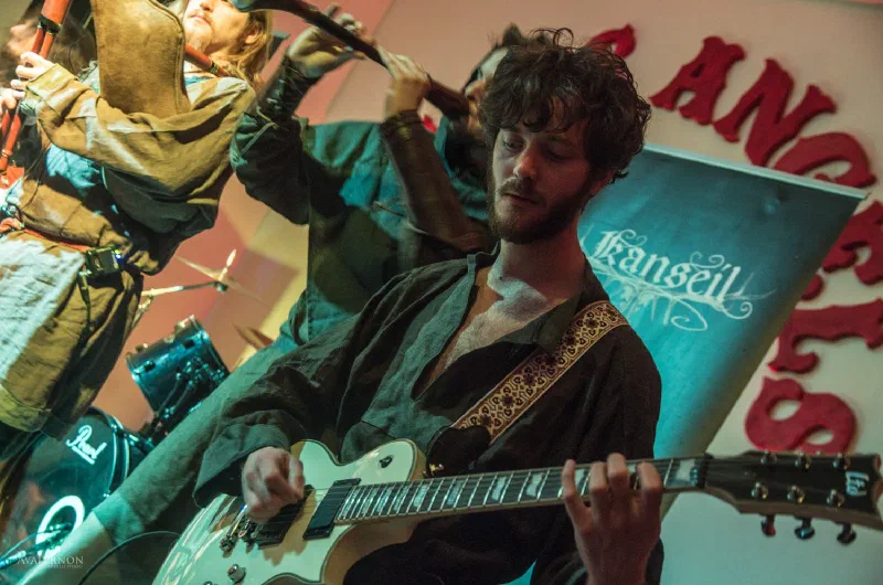 Guitarist playing on stage in front of a Kanseil banner